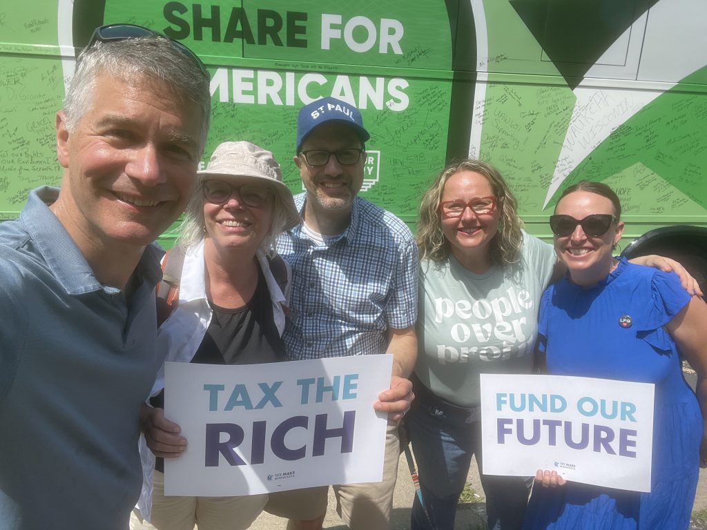 A five-person group including Minnesota Senate candidate Liz Reyer hold "Tax the rich" and "Fund our future" signs